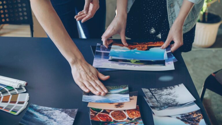 Designer arranging brand images with a color palette and markers on a desk