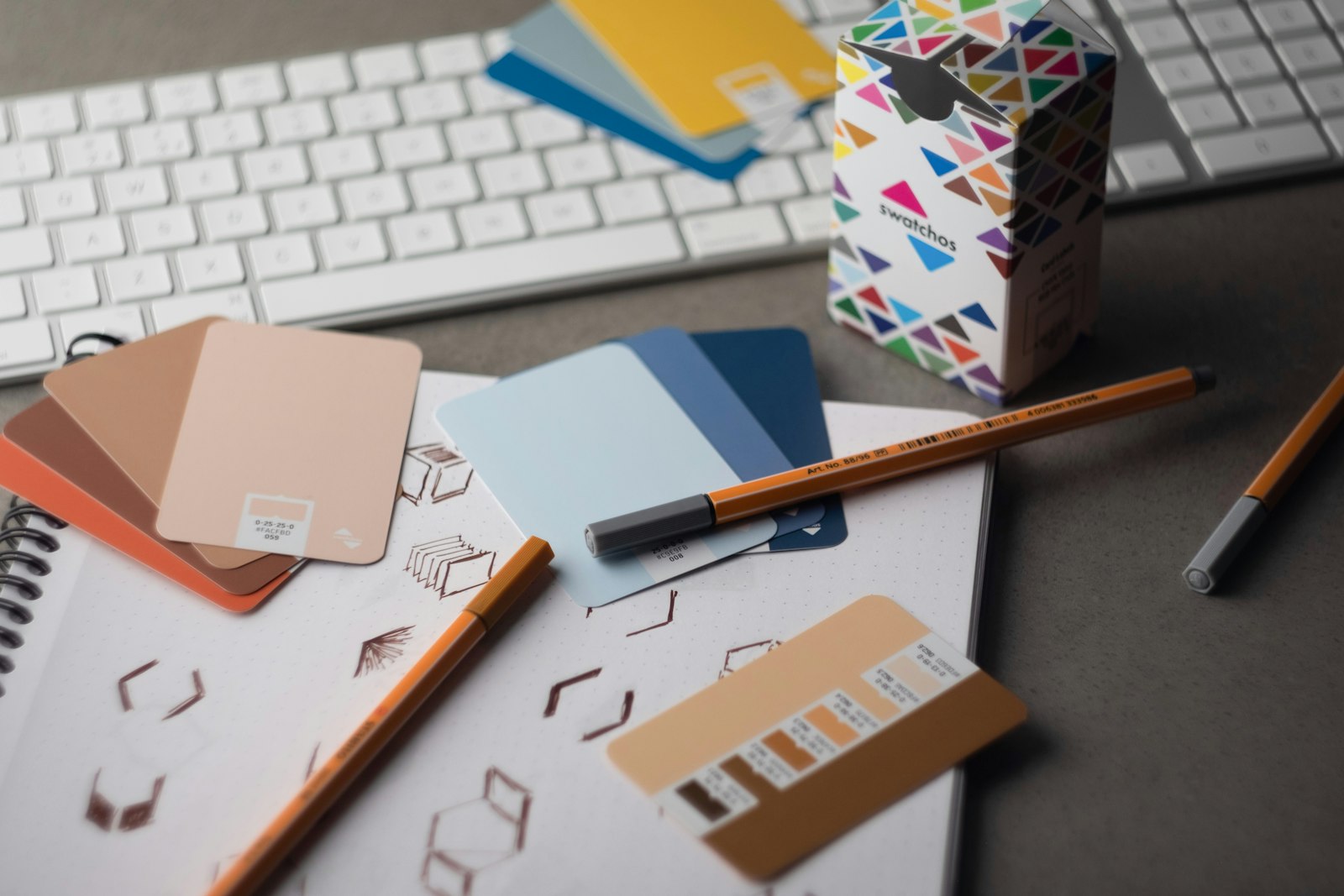 Color swatch cards with hex values on a designer's desk, used to plan a rebrand