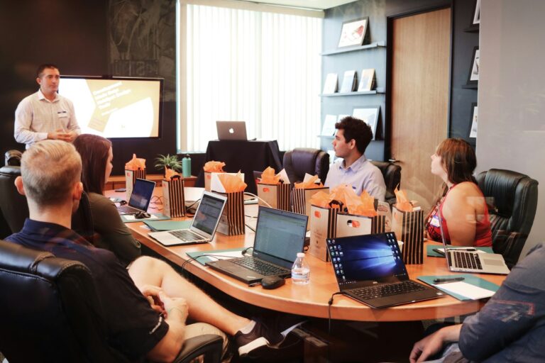 Marketing leader presenting a strategy to a small business team seated at a table with laptops